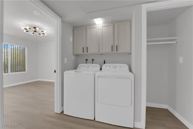 laundry room featuring a notable chandelier, washer and dryer, cabinets, and light hardwood / wood-style flooring