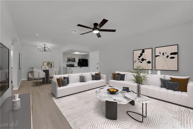 living room with ceiling fan with notable chandelier and light hardwood / wood-style flooring