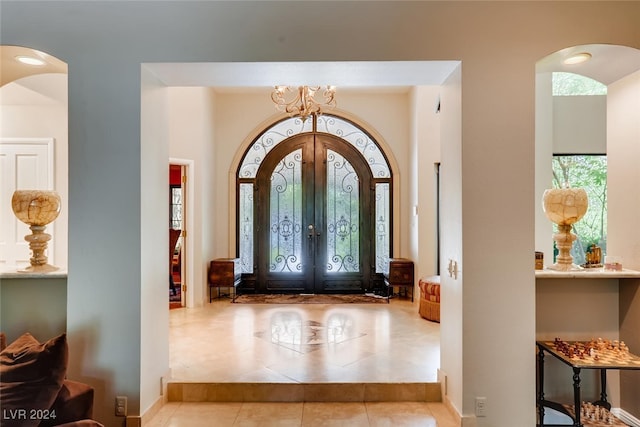 tiled entryway with french doors and an inviting chandelier