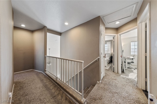 corridor with a textured ceiling and carpet floors