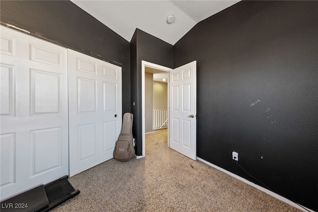 unfurnished bedroom with light carpet, a closet, and lofted ceiling