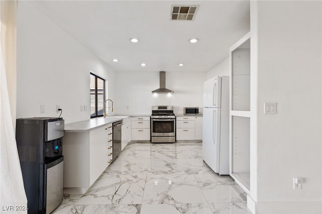 kitchen featuring white cabinetry, sink, wall chimney exhaust hood, stainless steel appliances, and kitchen peninsula