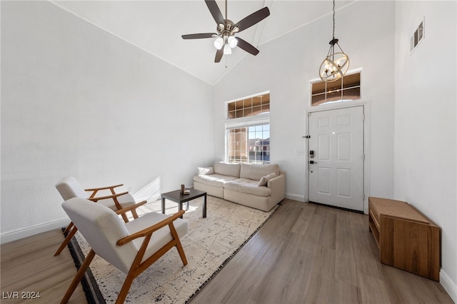 living room featuring hardwood / wood-style floors, high vaulted ceiling, and ceiling fan with notable chandelier