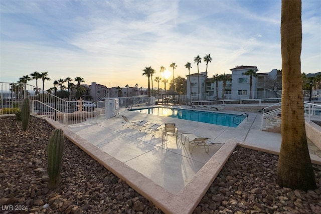 pool at dusk featuring a patio