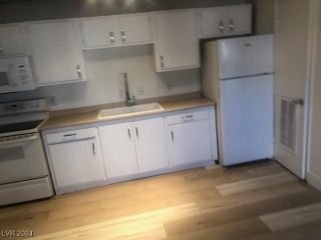 kitchen with white cabinetry, sink, light hardwood / wood-style floors, and white appliances