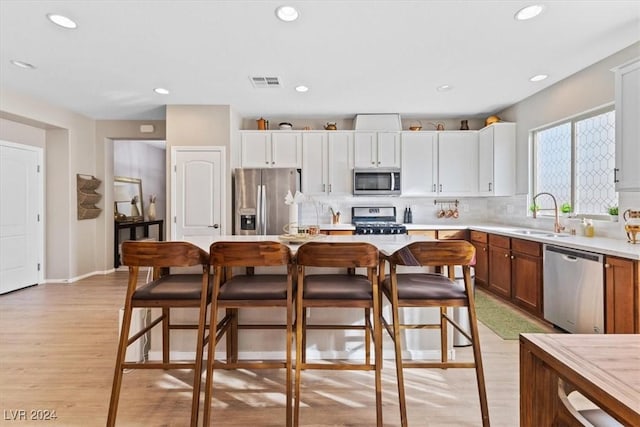 kitchen featuring decorative backsplash, appliances with stainless steel finishes, light wood-type flooring, sink, and white cabinets