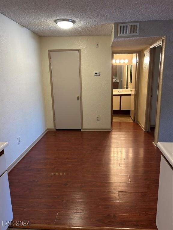 unfurnished room with dark hardwood / wood-style floors and a textured ceiling