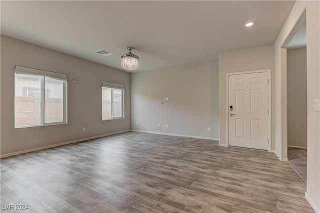 spare room with a notable chandelier and light wood-type flooring