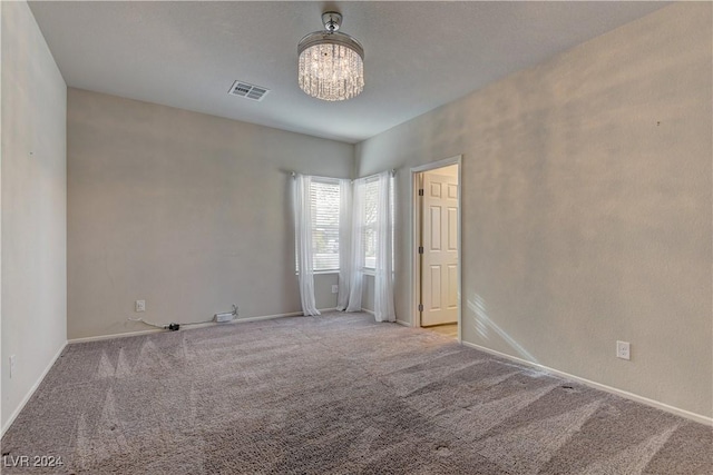 empty room with carpet and a notable chandelier