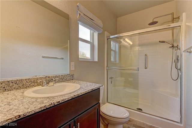 bathroom with toilet, an enclosed shower, and vanity