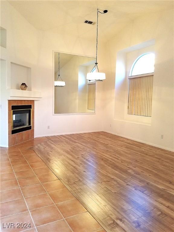 unfurnished living room with wood-type flooring, high vaulted ceiling, and a tiled fireplace