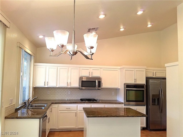 kitchen with white cabinetry, sink, vaulted ceiling, decorative light fixtures, and appliances with stainless steel finishes