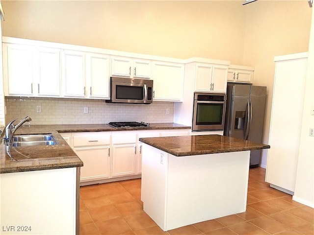 kitchen featuring appliances with stainless steel finishes, backsplash, a kitchen island, sink, and white cabinetry