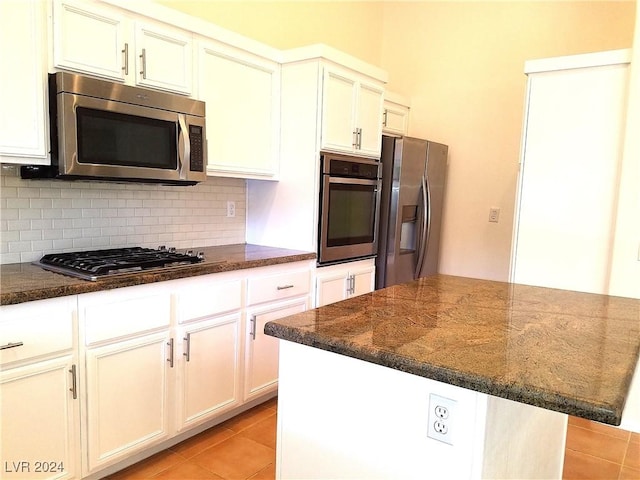 kitchen with a center island, dark stone countertops, appliances with stainless steel finishes, tasteful backsplash, and light tile patterned flooring