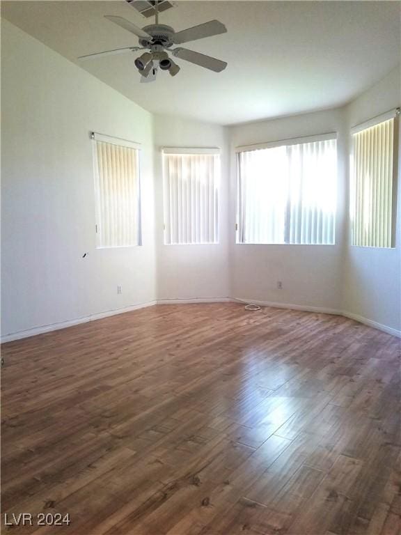 unfurnished room featuring dark hardwood / wood-style floors, a wealth of natural light, lofted ceiling, and ceiling fan