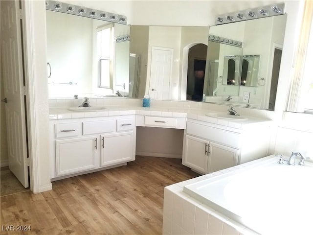 bathroom featuring hardwood / wood-style floors, vanity, and tiled bath