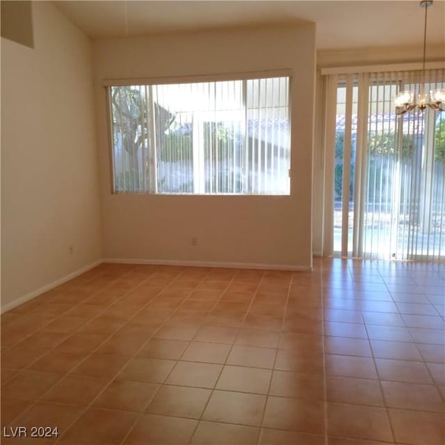 spare room with light tile patterned floors and an inviting chandelier