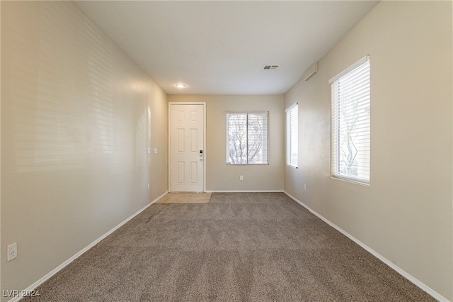 empty room with light colored carpet and a healthy amount of sunlight