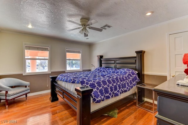 bedroom featuring ceiling fan, wood-type flooring, ornamental molding, and a textured ceiling