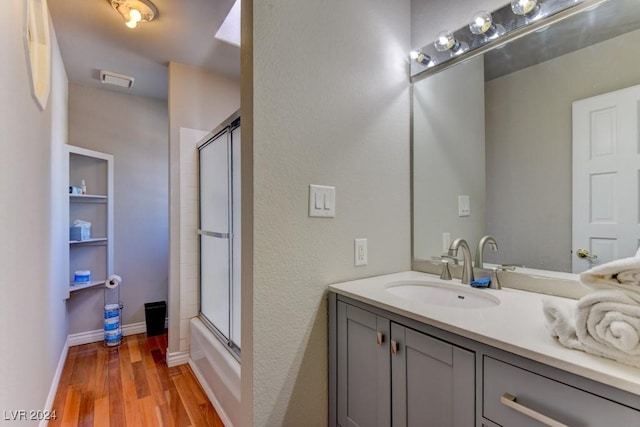 bathroom featuring vanity, hardwood / wood-style floors, and combined bath / shower with glass door