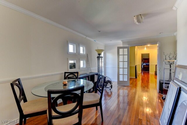 dining area with crown molding, light wood-type flooring, and french doors