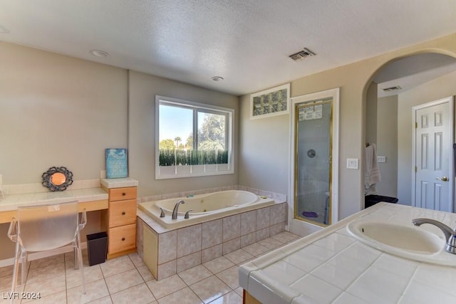 bathroom featuring tile patterned floors, vanity, plus walk in shower, and a textured ceiling