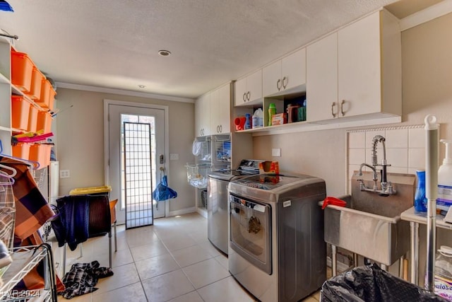 kitchen with crown molding, backsplash, washing machine and clothes dryer, white cabinets, and light tile patterned flooring