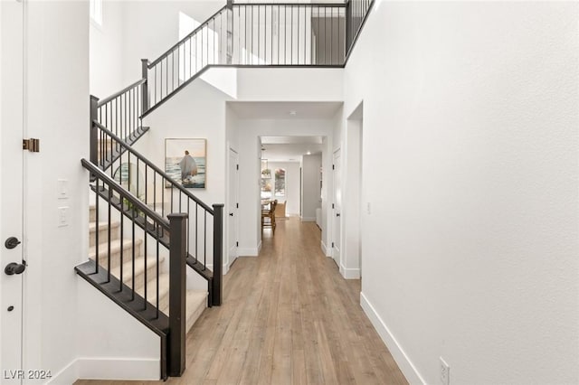 interior space with a towering ceiling and light hardwood / wood-style flooring