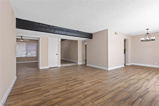 unfurnished living room with hardwood / wood-style flooring, ceiling fan with notable chandelier, and a textured ceiling