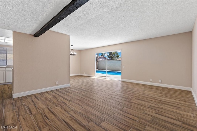 unfurnished living room with beam ceiling, wood-type flooring, and a textured ceiling