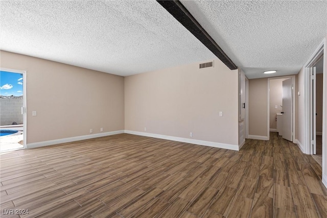 unfurnished living room featuring beam ceiling, wood-type flooring, and a textured ceiling