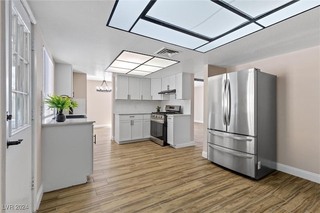 kitchen with white cabinets, backsplash, light hardwood / wood-style floors, and stainless steel appliances