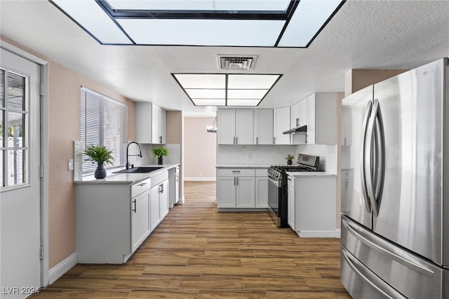 kitchen featuring decorative backsplash, dark hardwood / wood-style flooring, stainless steel appliances, sink, and white cabinetry