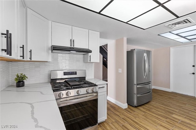 kitchen featuring light stone counters, white cabinetry, stainless steel appliances, and light hardwood / wood-style flooring