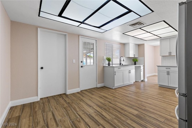 kitchen with stainless steel fridge, light hardwood / wood-style floors, and white cabinetry