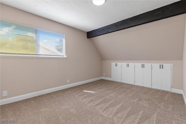 additional living space featuring lofted ceiling with beams, light colored carpet, and a textured ceiling