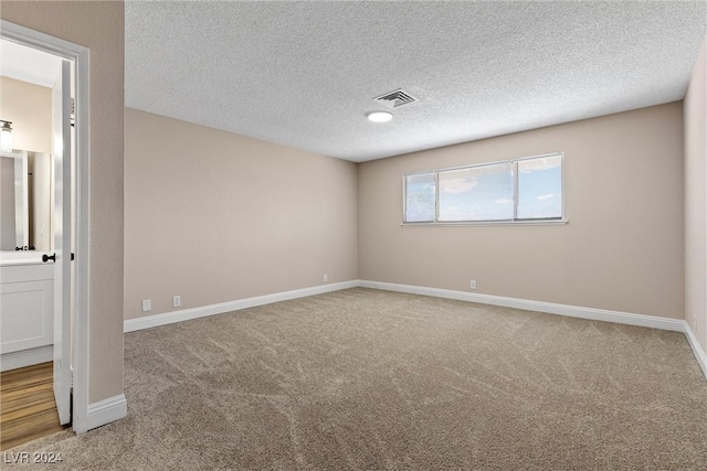 carpeted empty room with a textured ceiling