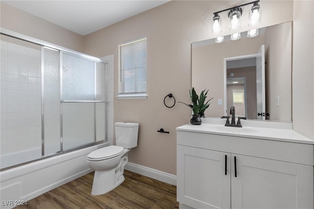 full bathroom featuring wood-type flooring, vanity, toilet, and bath / shower combo with glass door