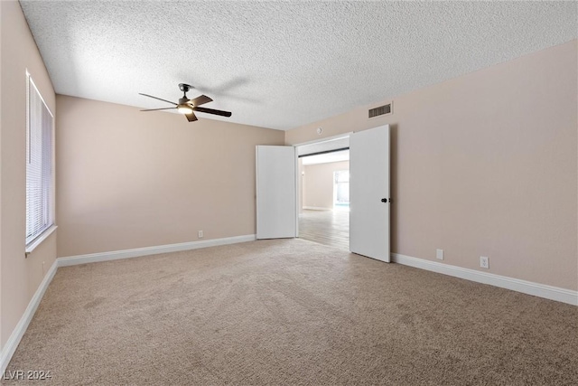 carpeted empty room with ceiling fan and a textured ceiling