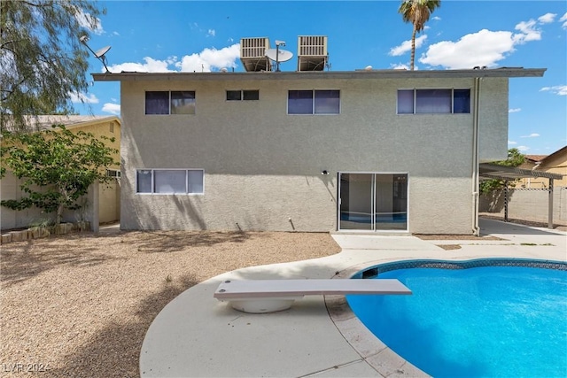 rear view of property with a fenced in pool and a patio