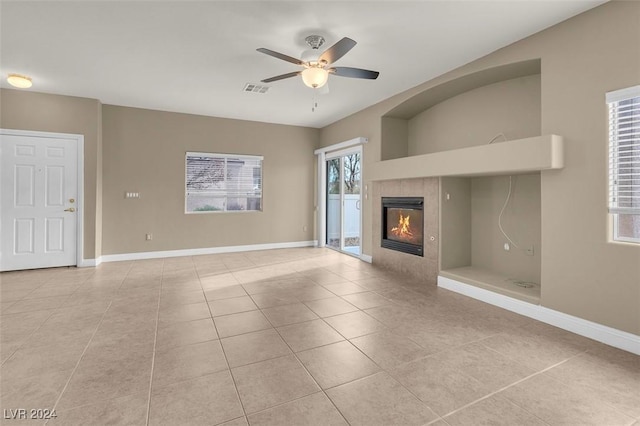 unfurnished living room with a tile fireplace, light tile patterned flooring, and ceiling fan