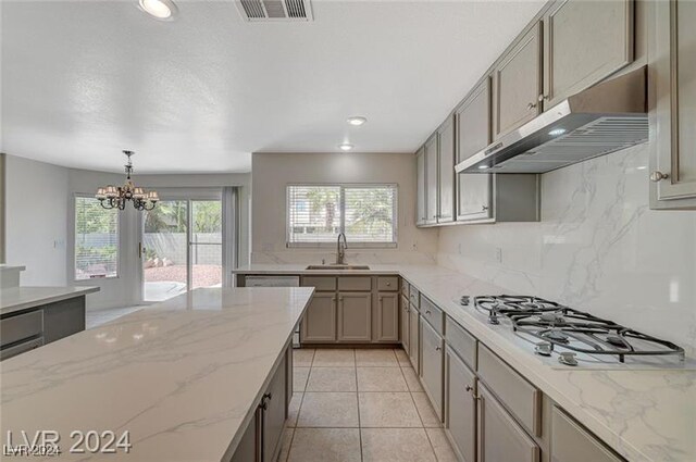 kitchen featuring sink, tasteful backsplash, a notable chandelier, decorative light fixtures, and stainless steel gas stovetop