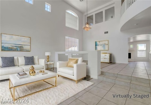 living room featuring plenty of natural light, a towering ceiling, a chandelier, and tile patterned flooring