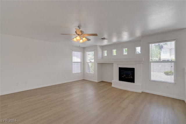 unfurnished living room featuring light wood-type flooring, a wealth of natural light, and ceiling fan