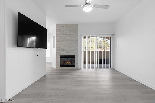 unfurnished living room featuring a tile fireplace, ceiling fan, and wood-type flooring