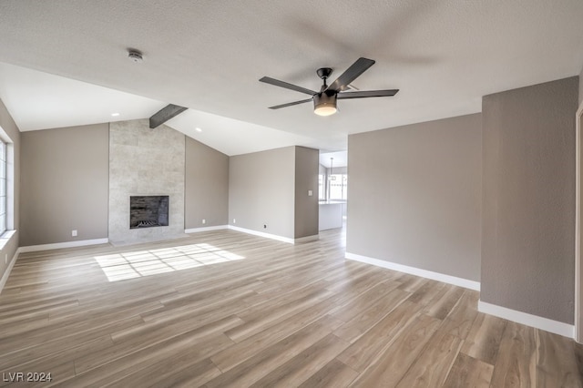 unfurnished living room featuring vaulted ceiling with beams, ceiling fan, a fireplace, and light wood-type flooring