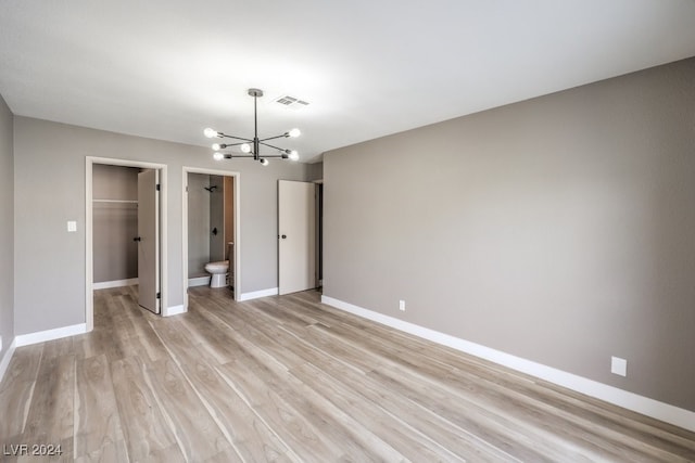 unfurnished room featuring an inviting chandelier and light wood-type flooring