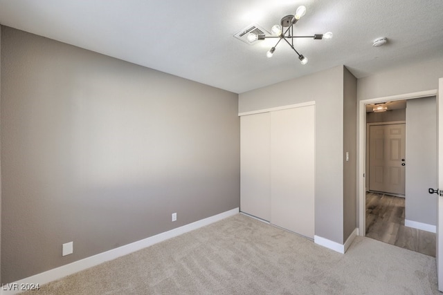 unfurnished bedroom with carpet, a notable chandelier, and a closet