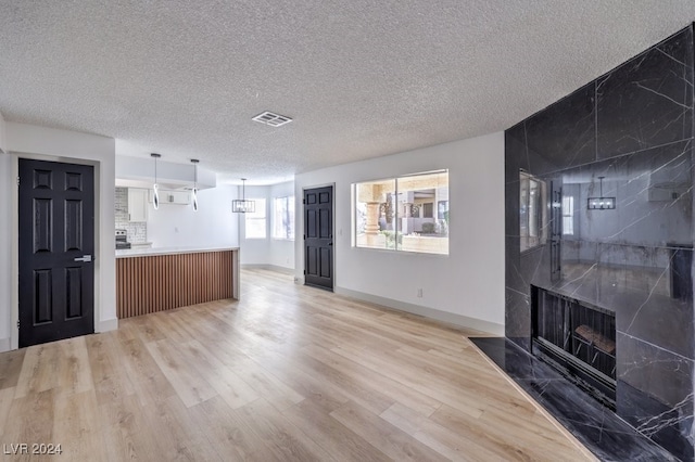 unfurnished living room with a fireplace, a textured ceiling, and light hardwood / wood-style flooring