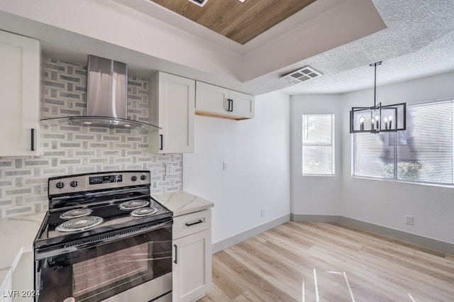 kitchen with stainless steel electric stove, light stone countertops, white cabinets, and wall chimney range hood